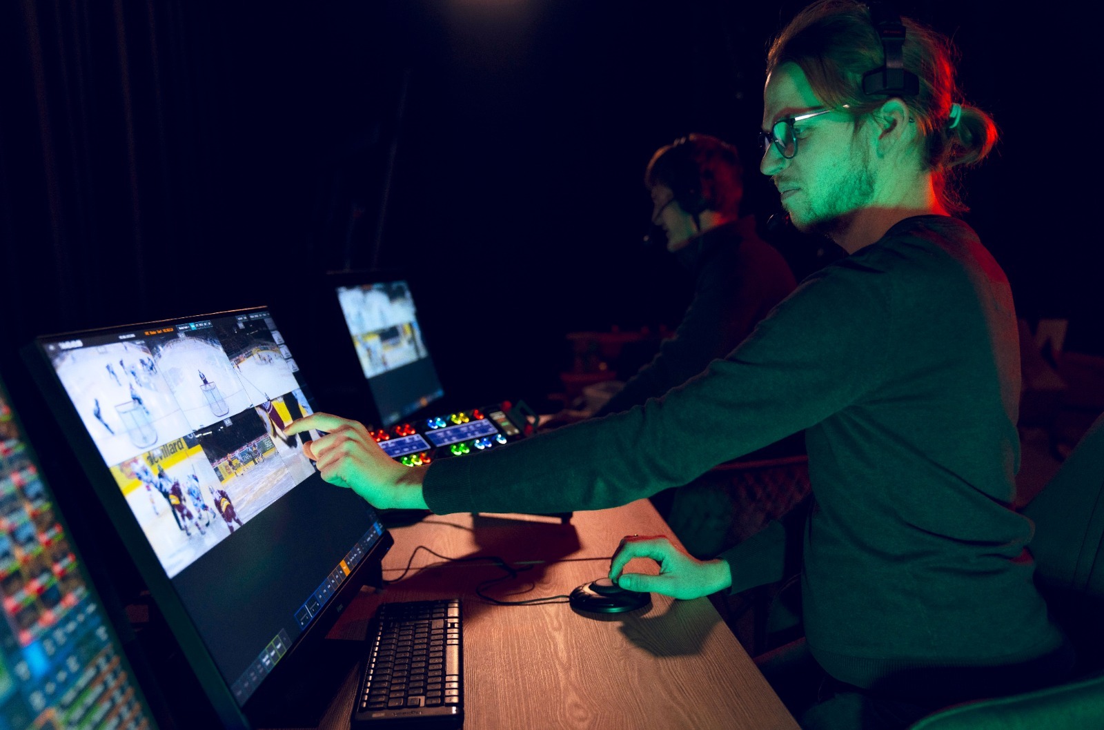 Man at broadcast control desk pushing buttons and looking at a screen